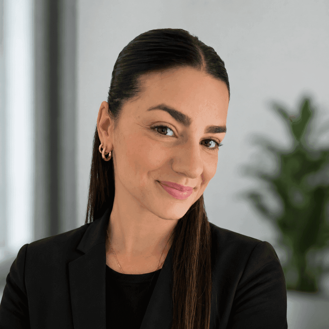 Smiling young professional woman with dark hair wearing a black blazer.